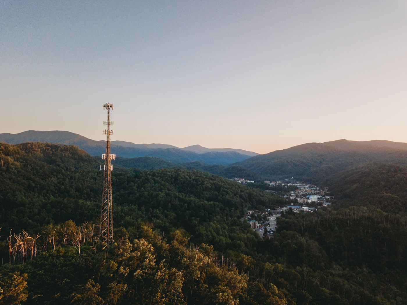Mobilmast i skogen med berg i bakgrunden