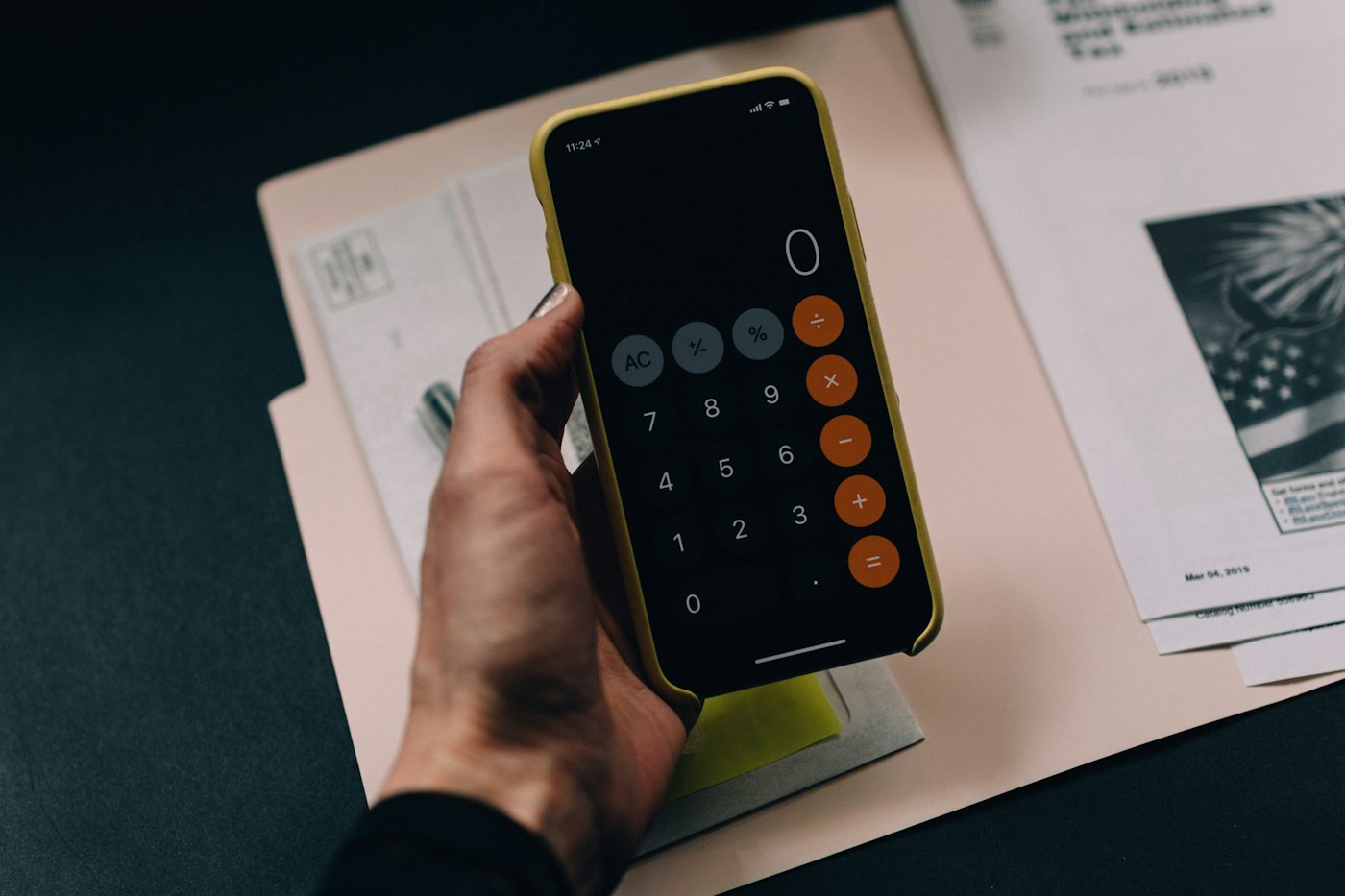 Hand håller en mobil med miniräknare över räkningar