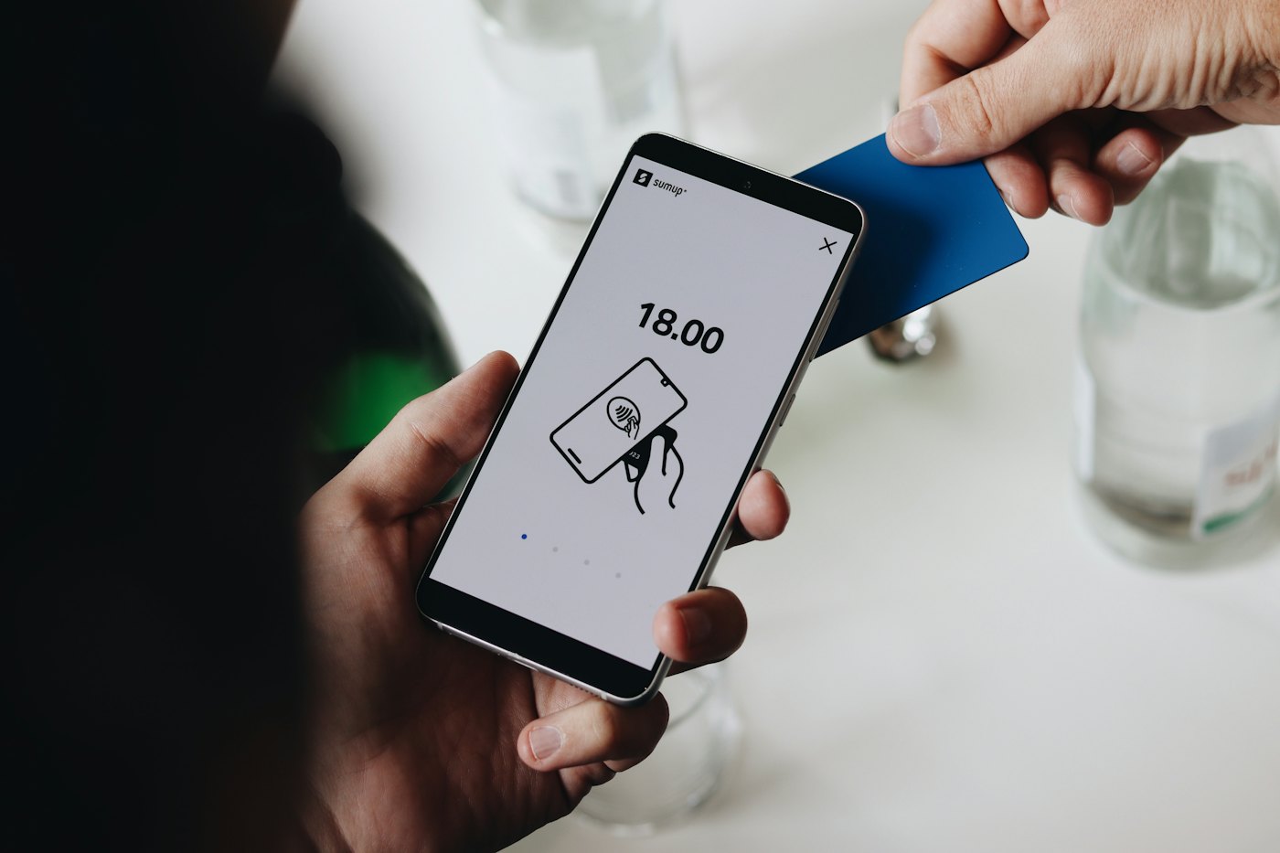 Händer betalar med kort och laddar en mobil