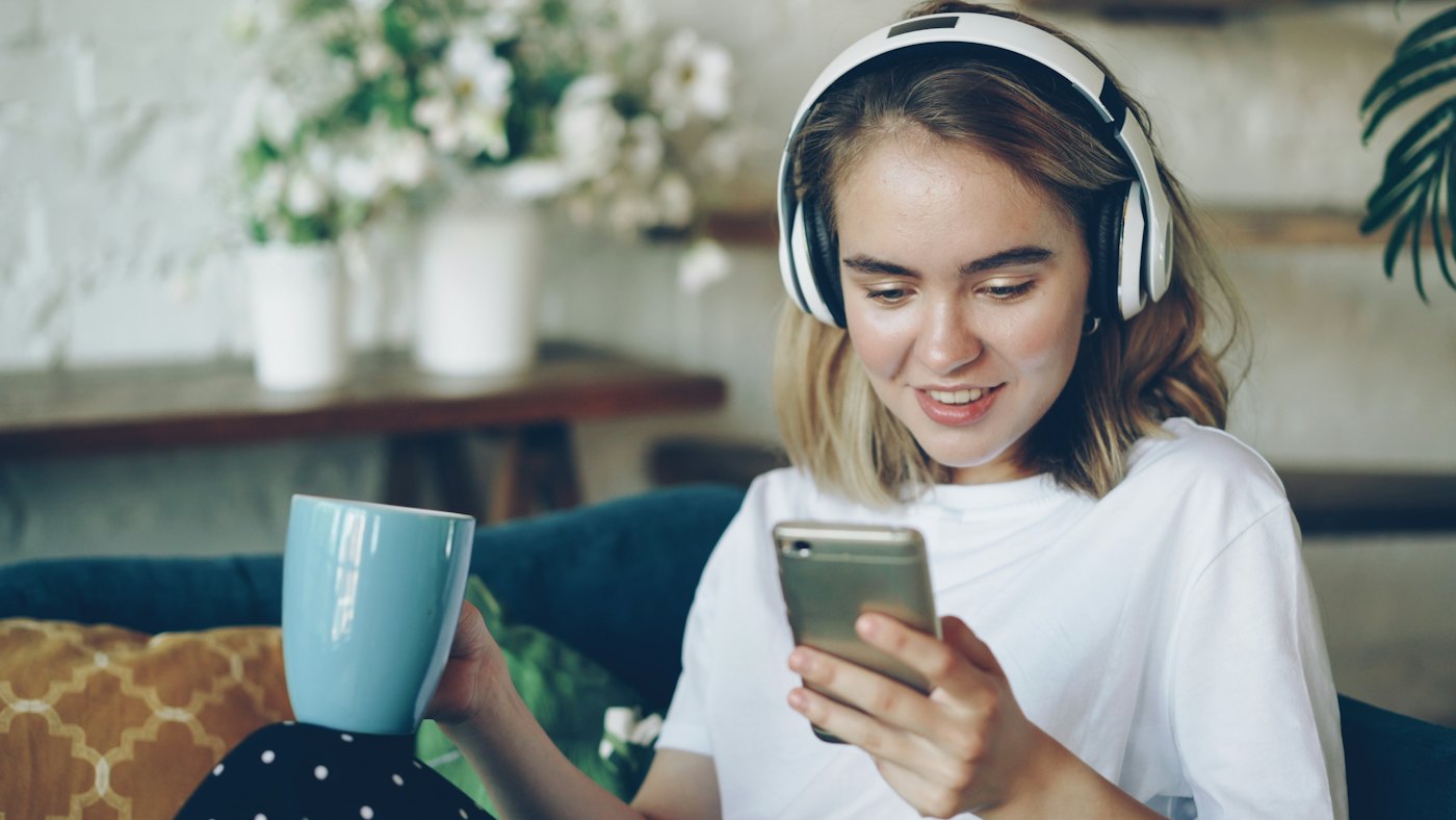 Kvinna med hörlurar som tittar på mobilen